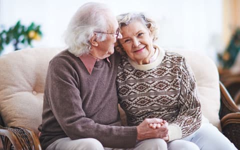 Elderly Couple Hugging On Sofa