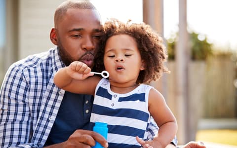 Father Blowing Bubbles With Child