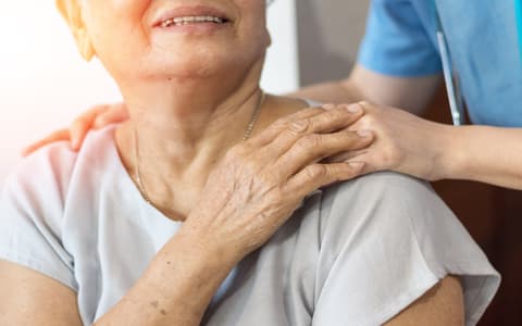 Elderly Woman Holding Carer Hand On Shoulder