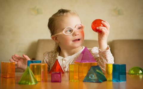 Young Girl With Down Syndrome Playing With Ball On Table