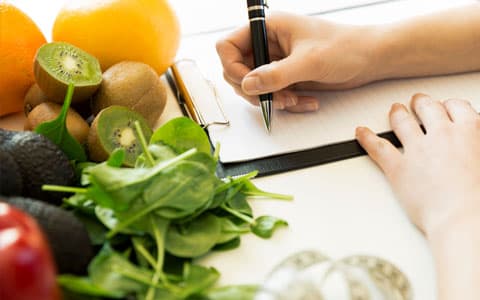 Person Writing On Paper Attached To Clipboard