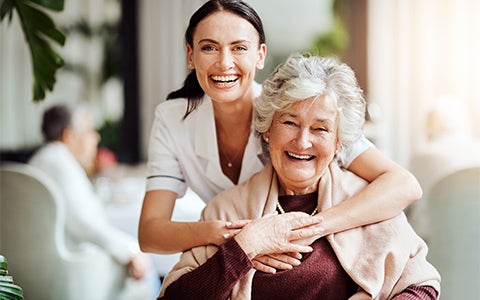 Female Carer Hugging Elderly Lady And Smiling