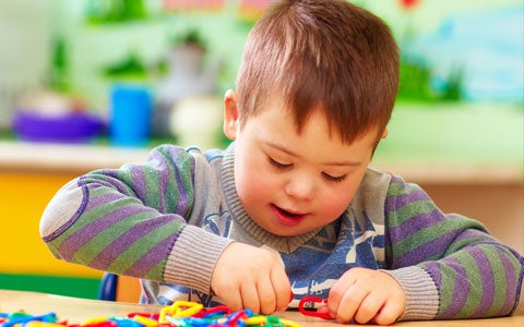 Young Boy With Down Syndrome Playing At Table